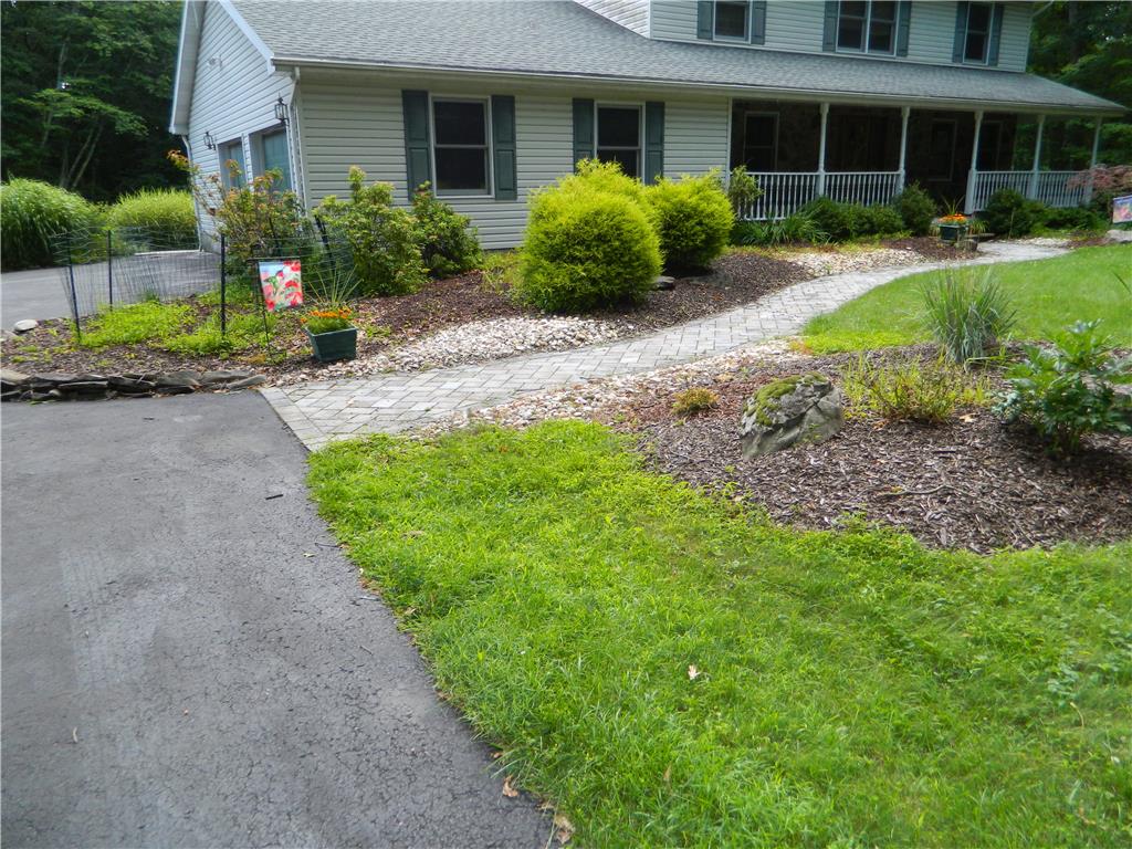 328 Pin Oak Road Stroudsburg, PA 18360 - Photo 5 of 42 A well-maintained lawn and paved pathway lead to a charming residence with a welcoming front porch.