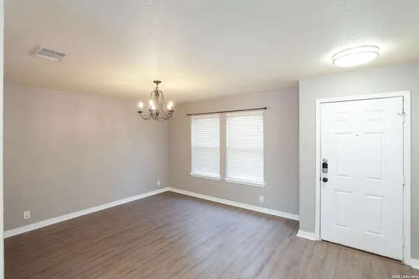 an empty room with wooden floor cabinet and windows