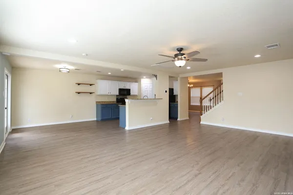 a view of a big room with wooden floor and a kitchen