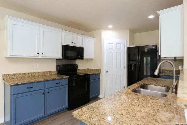 a kitchen with granite countertop wooden cabinets and black stainless steel appliances