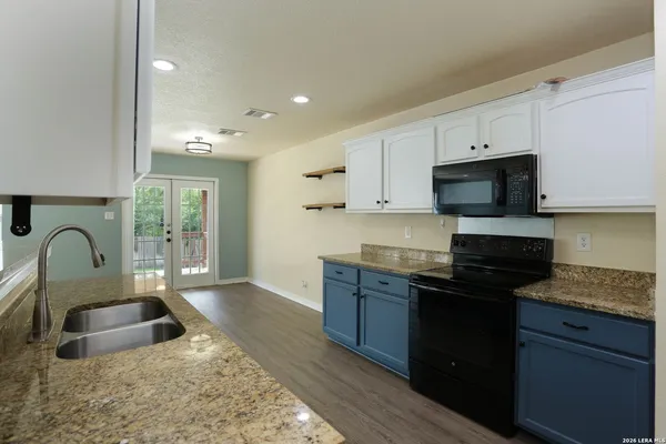 a kitchen with granite countertop a stove a sink and a microwave
