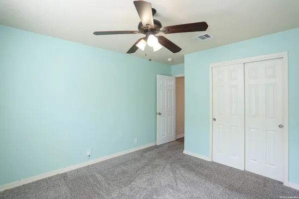 an empty room with a ceiling fan and carpet
