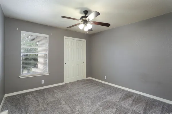 an empty room with a window and a fan