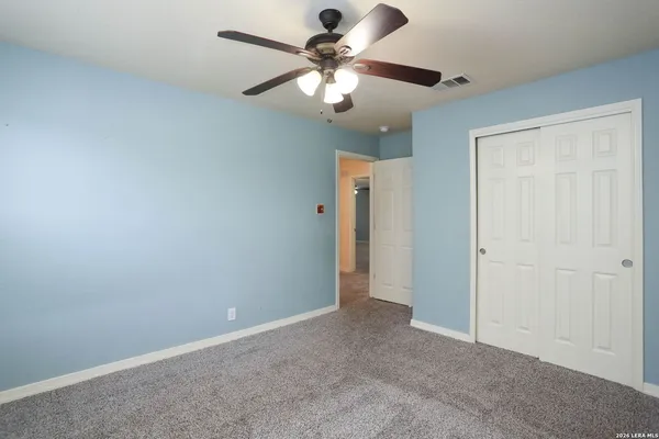 a view of an empty room and chandelier fan