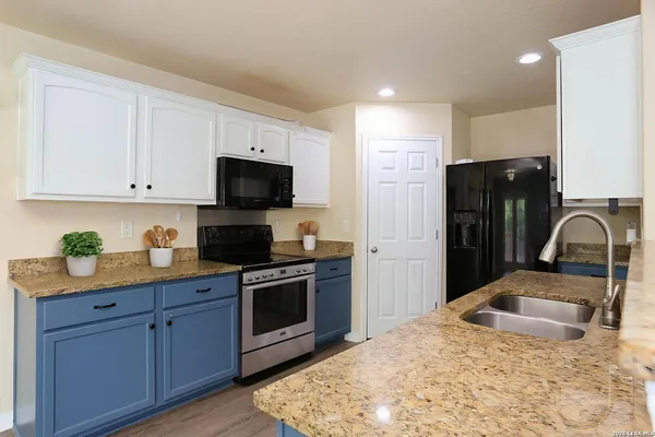 a kitchen with stainless steel appliances granite countertop a stove a sink dishwasher a refrigerator and a stove with wooden floor