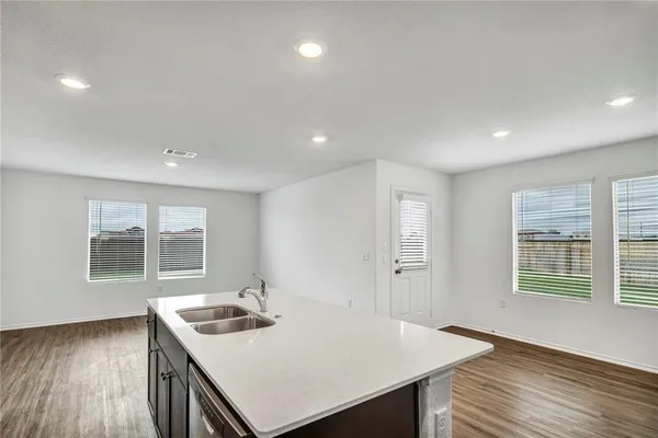 a view of a kitchen that has a sink a window and wooden floor
