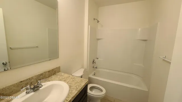 a bathroom with a granite countertop bathtub sink vanity mirror and toilet