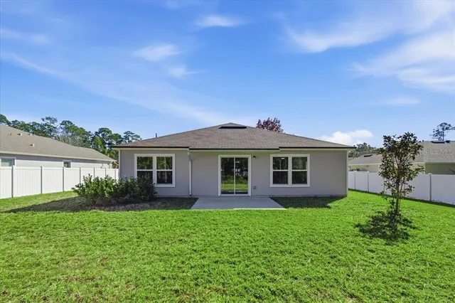 a view of a yard in front of a house with plants and large tree