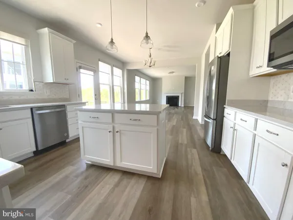 a kitchen with stainless steel appliances granite countertop a refrigerator a sink dishwasher a stove and white countertops with wooden floor