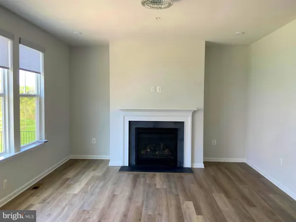 a view of an empty room with wooden floor fireplace and a window