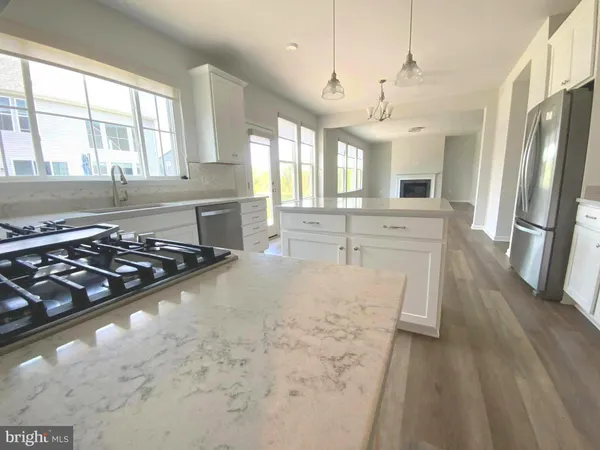 a large kitchen with stainless steel appliances granite countertop a stove a sink dishwasher a refrigerator white cabinets with wooden floor