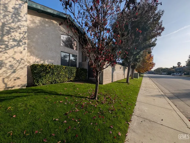 a view of a yard in front of a house with a large tree
