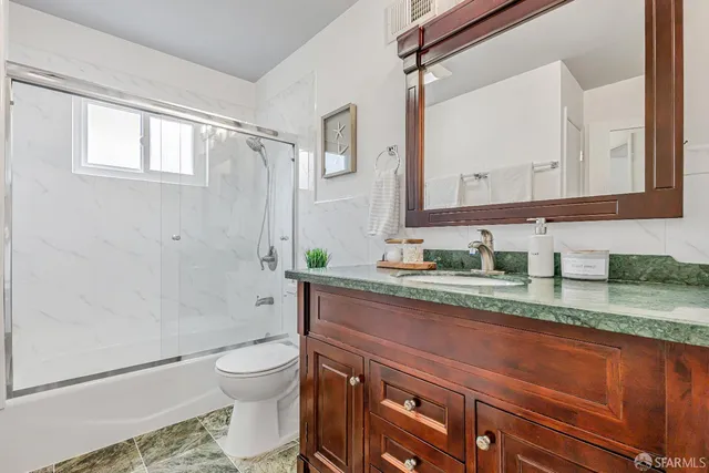 a bathroom with a granite countertop toilet sink and mirror