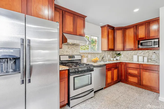 a kitchen with stainless steel appliances granite countertop a refrigerator a stove and a sink