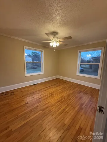 a view of an empty room with a window and wooden floor