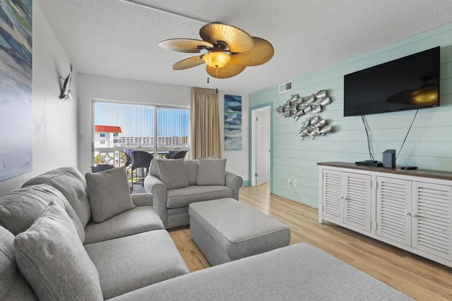a living room with furniture a flat screen tv and kitchen view