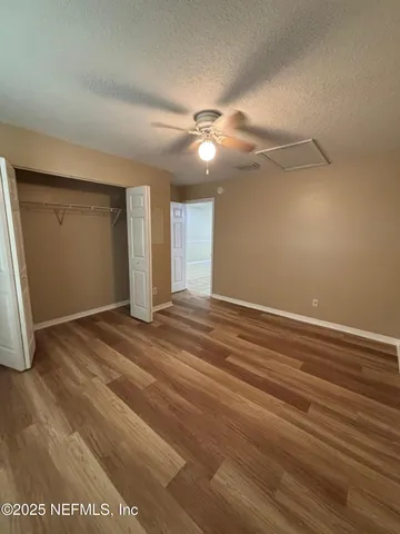 an empty room with wooden floor fan and windows