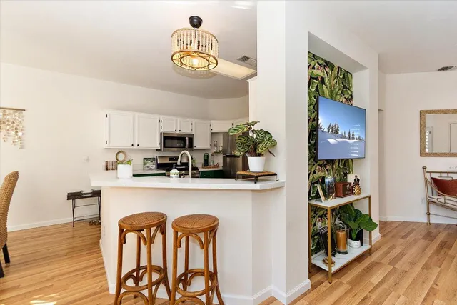 a kitchen with stainless steel appliances granite countertop a dining table chairs stove and white cabinets