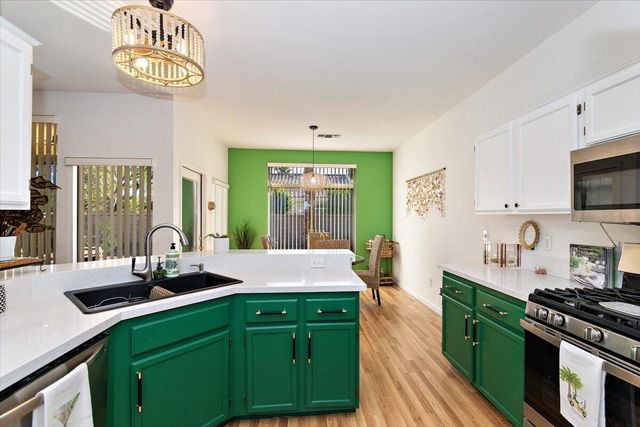 a kitchen with stainless steel appliances granite countertop a sink a stove and a wooden floors