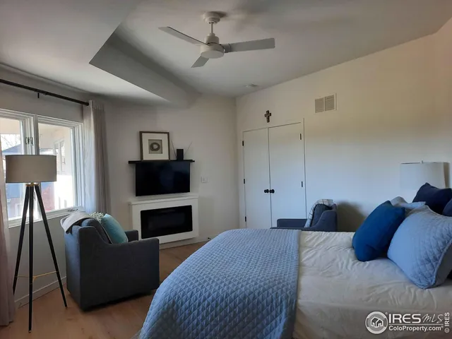 a bedroom with bed a ceiling fan and a fireplace