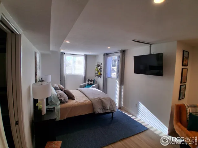 a bedroom with a bed wooden floor and a flat screen tv