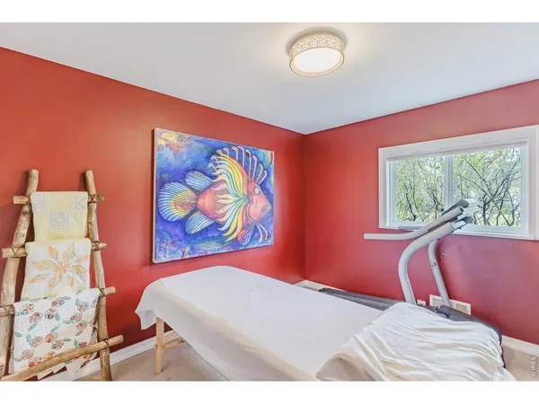 a bedroom with a bed painting on wall and a large window