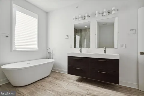 a spacious bathroom with a tub double sink and mirror