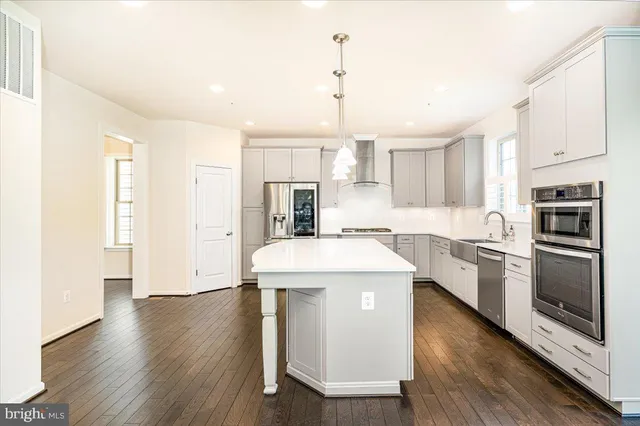 a large kitchen with stainless steel appliances a large kitchen island hardwood floor sink stove and a center island