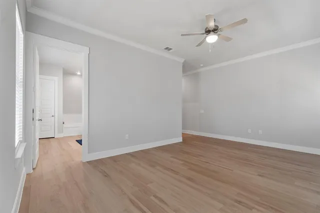 an empty room with wooden floor and ceiling fan