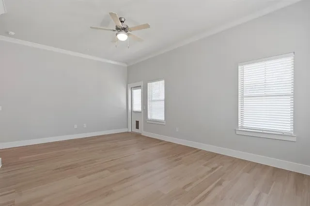 an empty room with wooden floor ceiling fan and windows