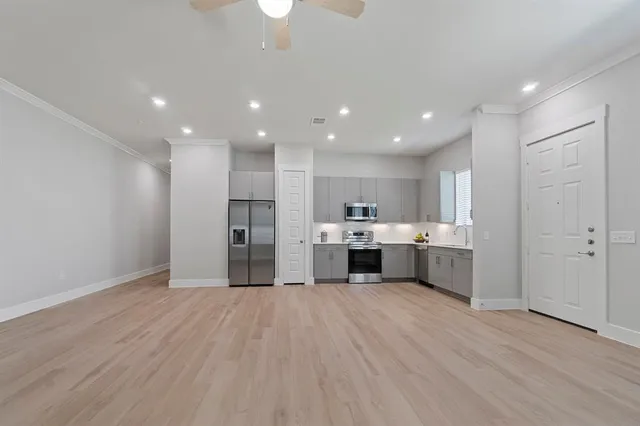 a kitchen with stainless steel appliances kitchen island wooden floors and white cabinets