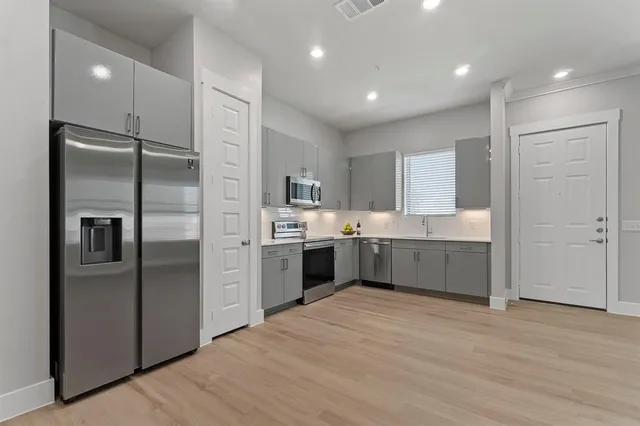 a large kitchen with a large counter top stainless steel appliances and cabinets