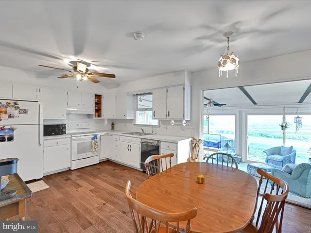 a large kitchen with granite countertop a stove a sink dishwasher a dining table and chairs with a large window