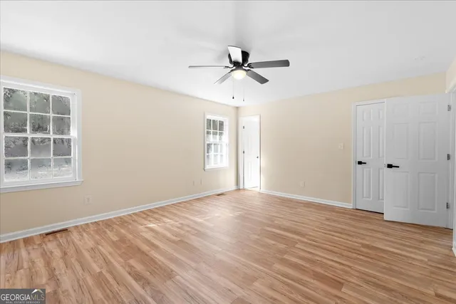 a view of empty room with wooden floor and fan