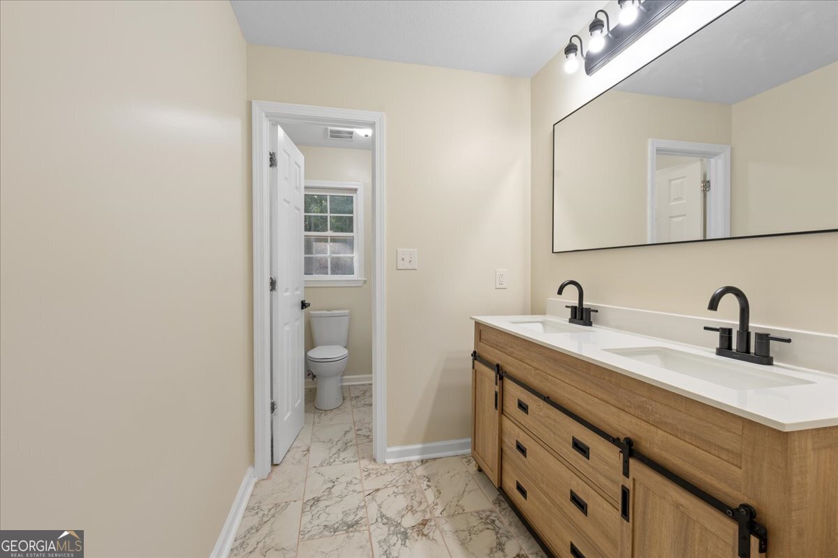 126 Waterfront Way Warner Robins, GA 31093 - Photo 29 of 60 a bathroom with a double vanity sink and a toilet