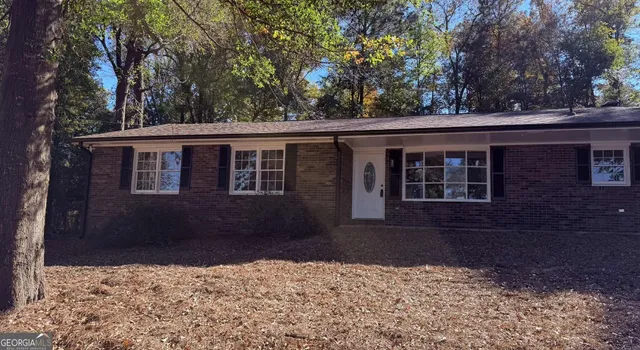 a backyard of a house with large trees and outdoor seating