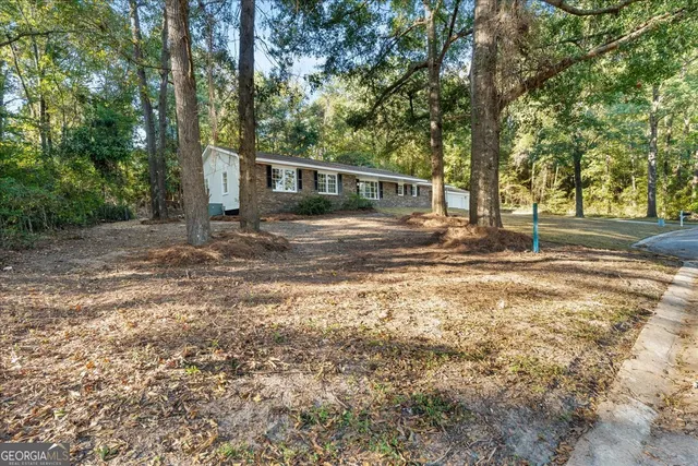 a view of a house with a yard and trees in the background