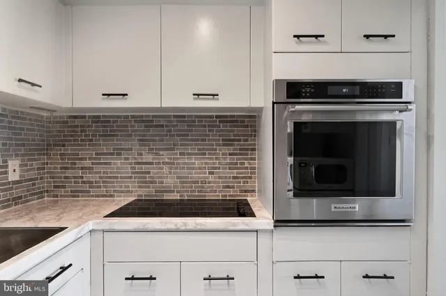 a kitchen with granite countertop white cabinets and stainless steel appliances