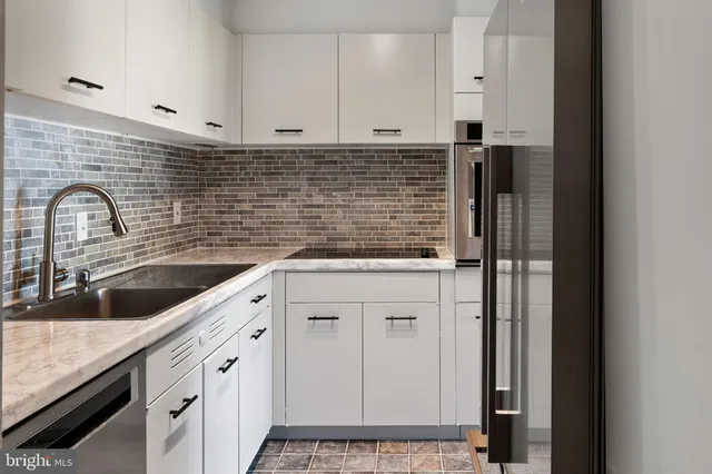 a kitchen with granite countertop white cabinets and stainless steel appliances