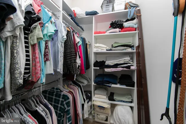 a view of walk in closet with clothes and shoes