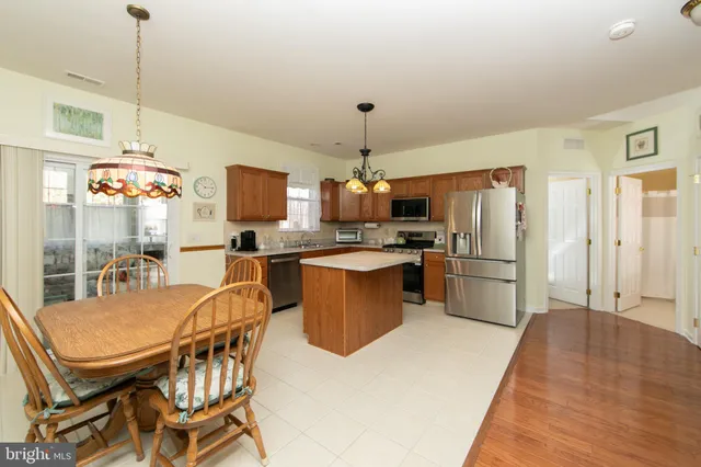 a kitchen with granite countertop a table chairs refrigerator and microwave