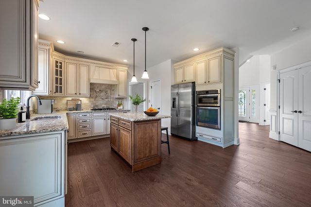 a kitchen with stainless steel appliances a stove a sink a refrigerator a center island and wooden floor