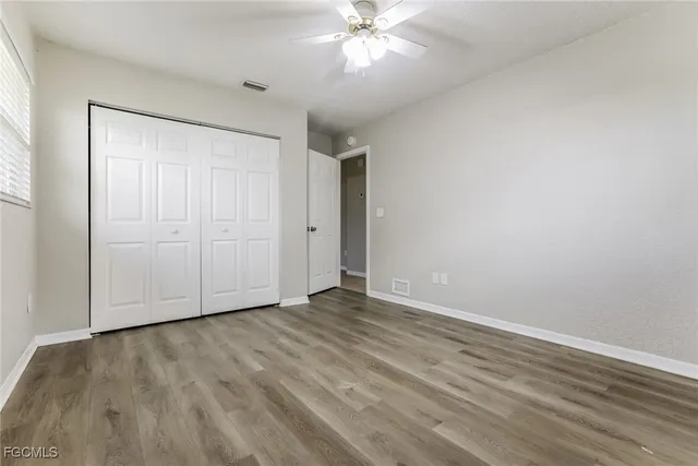 a view of an empty room with wooden floor and a ceiling fan