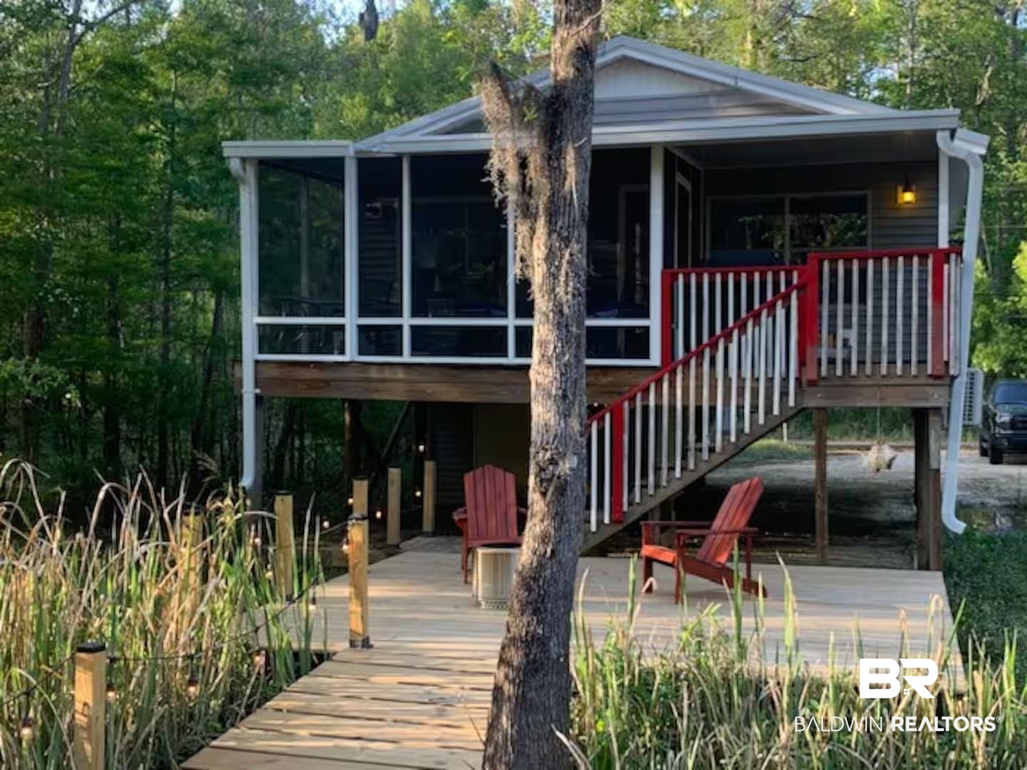42090 Bayou Road Bay Minette, AL 36507 - Photo 1 of 13 Back of property featuring a deck, a patio area, a sunroom, and view of scattered trees