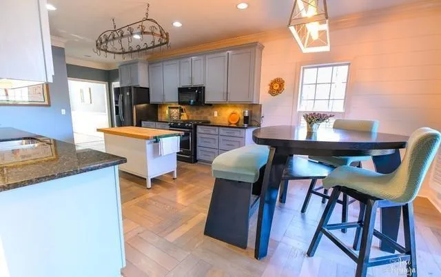 a kitchen with stainless steel appliances kitchen island granite countertop a table chairs in it and wooden floors