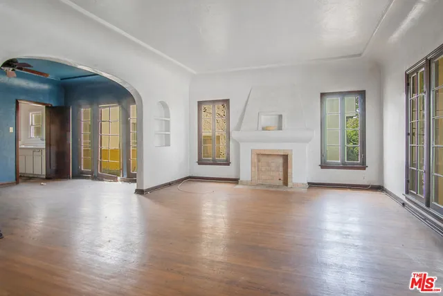 an empty room with wooden floor a fireplace and windows