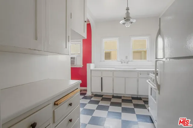 a kitchen with a sink a stove and white cabinets