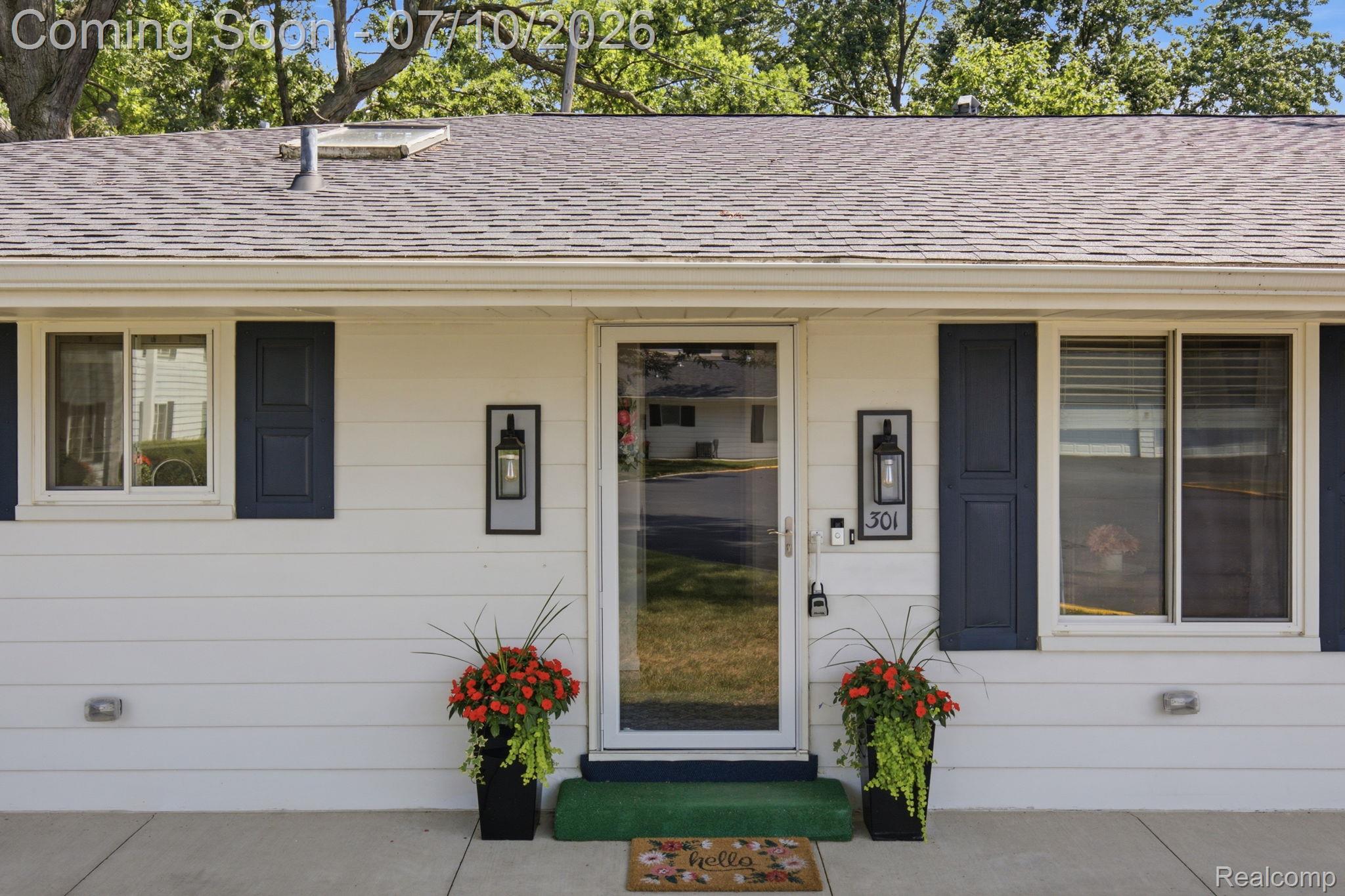 1501 River Road, Unit 301 St. Clair, MI 48079 - Photo 1 of 32 White siding facade featuring a full-light storm door, dark louvered shutters, exposed aggregate concrete porch, and dual exterior wall lanterns