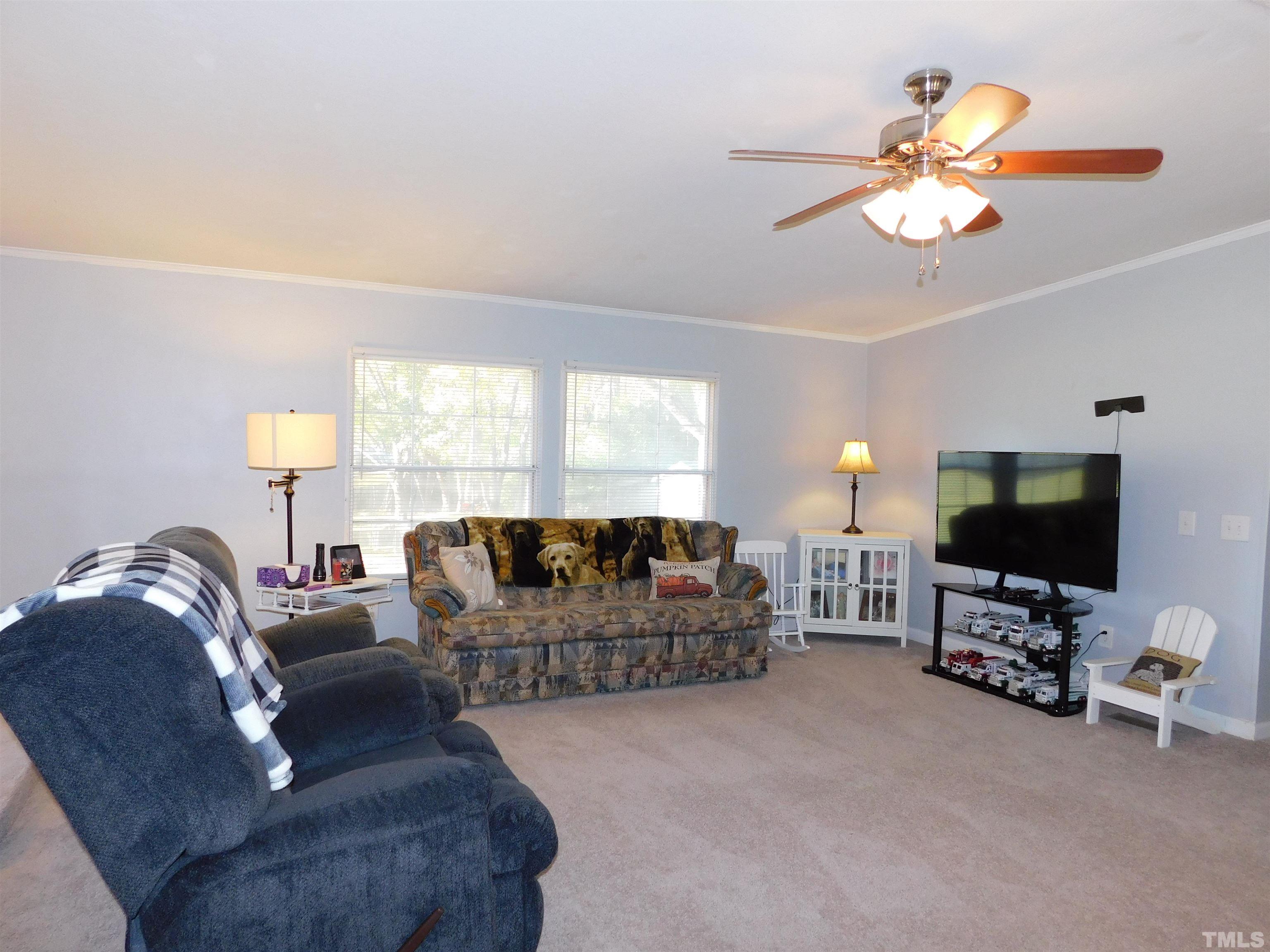 7180 Driver Road Zebulon, NC 27597 - Photo 3 of 19 a living room with furniture a chandelier and a flat screen tv