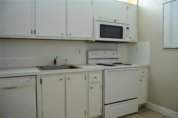 a kitchen with stainless steel appliances granite countertop white cabinets sink and a microwave